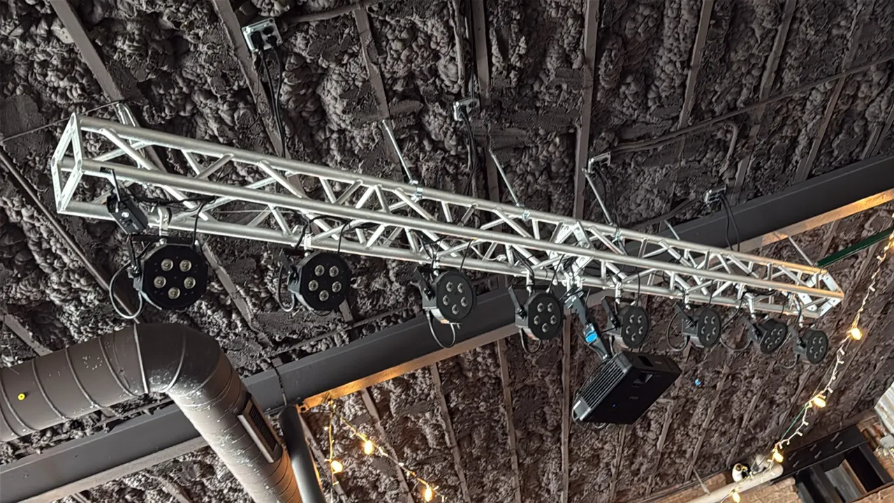 Aluminum box lighting truss with (12) LED PAR can lights. Features modular aluminum truss construction with clamp-mounted stage lights. Approximately