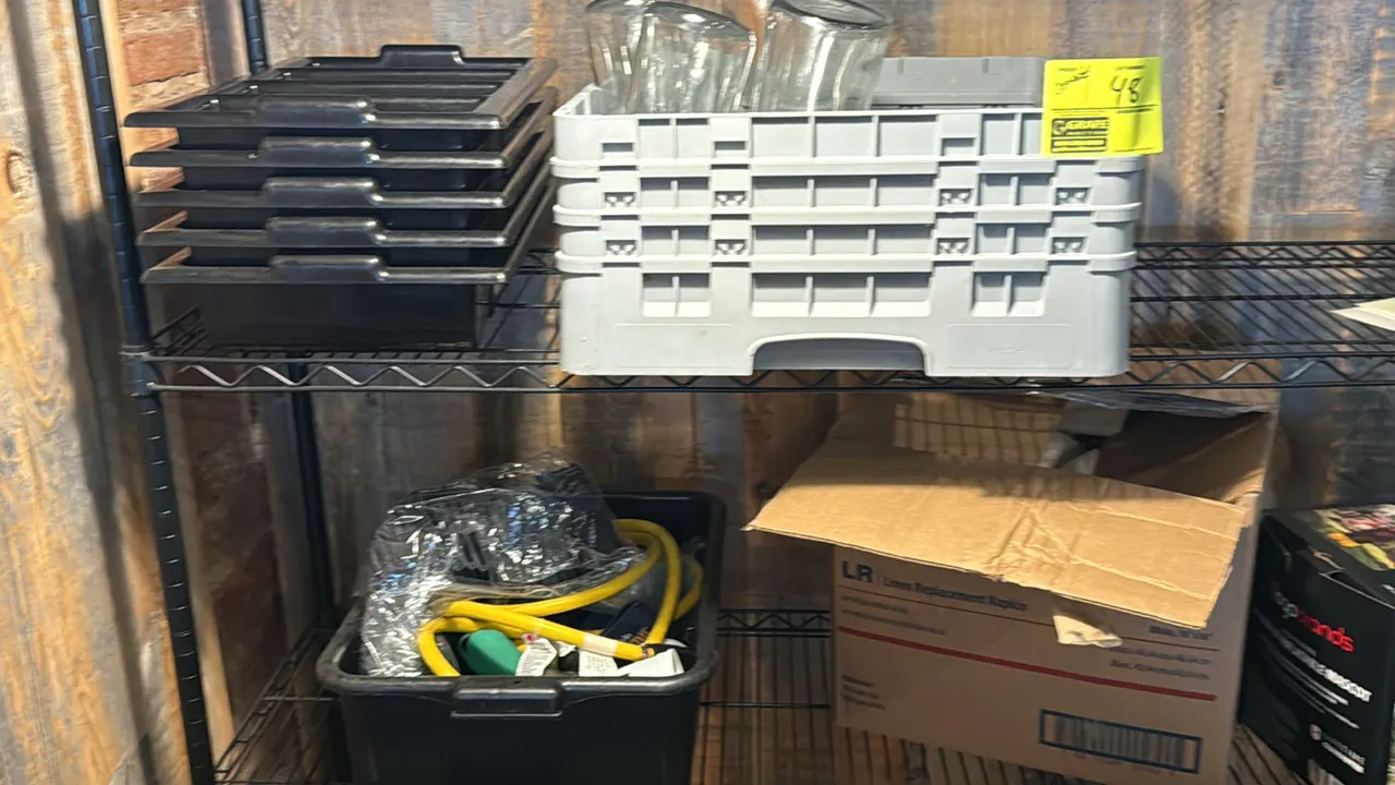 Assorted restaurant supplies. Includes glass water carafes with a glass rack, stacked plastic 4-compartment flatware organizers, a bus tub containing
