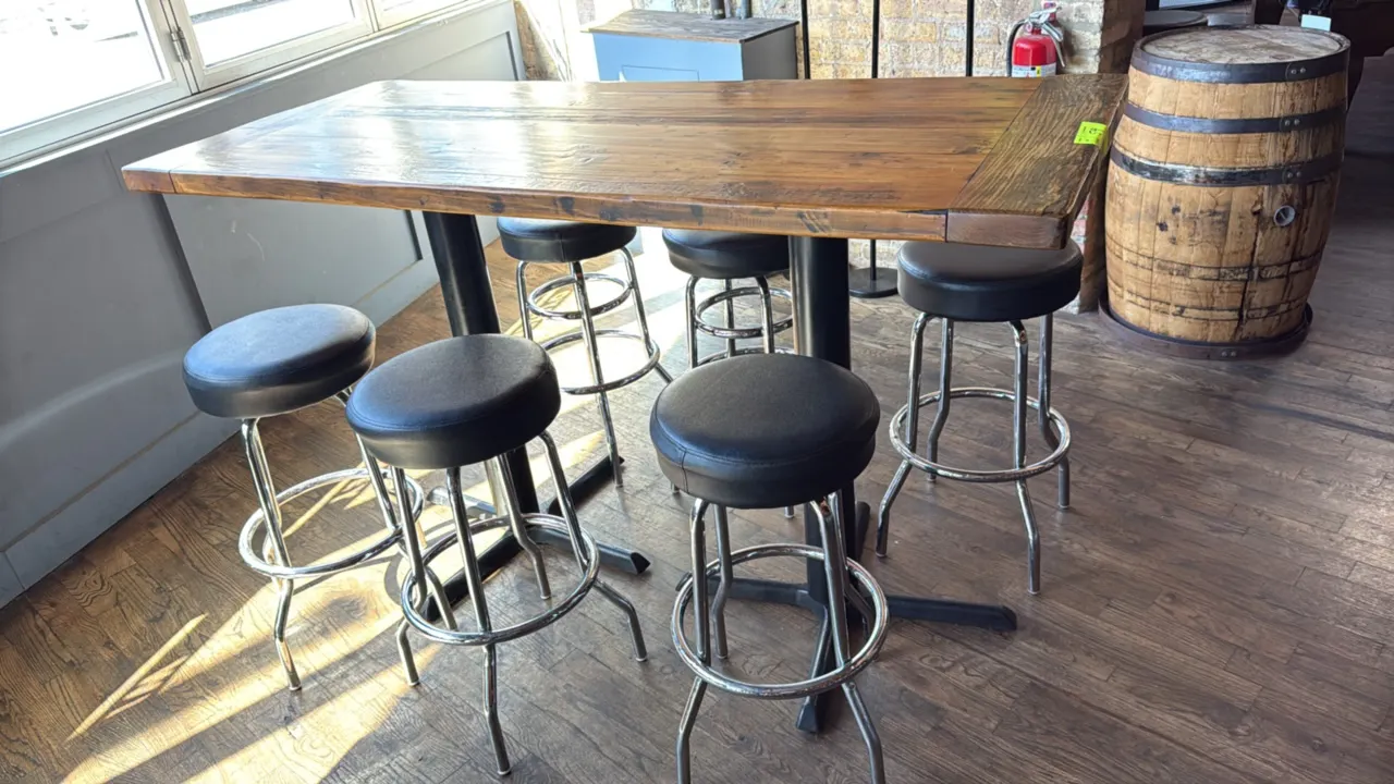 Wood bar height table with (6) swivel barstools. Features a plank wood top, mounted on dual black metal pedestal bases. Includes (6) barstools featuri