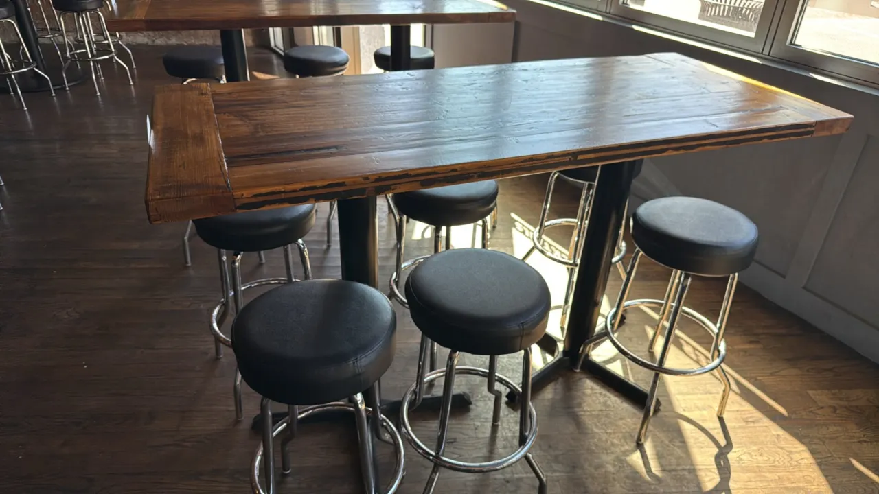 Wood bar height table with (6) swivel barstools. Table features a wood plank top on a black dual-pedestal metal base, measuring 72"L x 30"W x 42.5"H.
