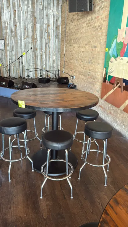 Wood bar height table with (5) swivel barstools. Features a round wood plank-style top with metal perimeter banding and a black metal pedestal base. I
