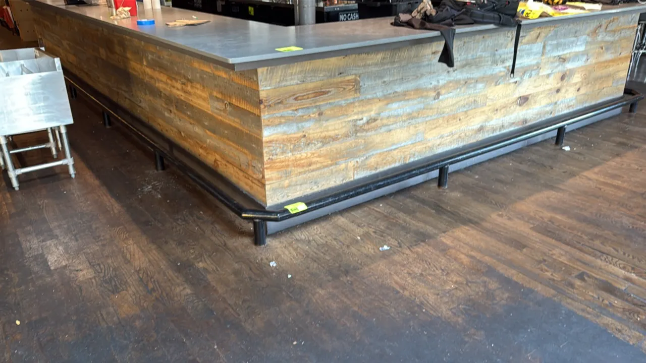 Metal bar foot rail. Features U-shaped layout and black tubular construction with floor-mounted support posts. Dimensions: 24'2" x 14'9". Note: Bar co