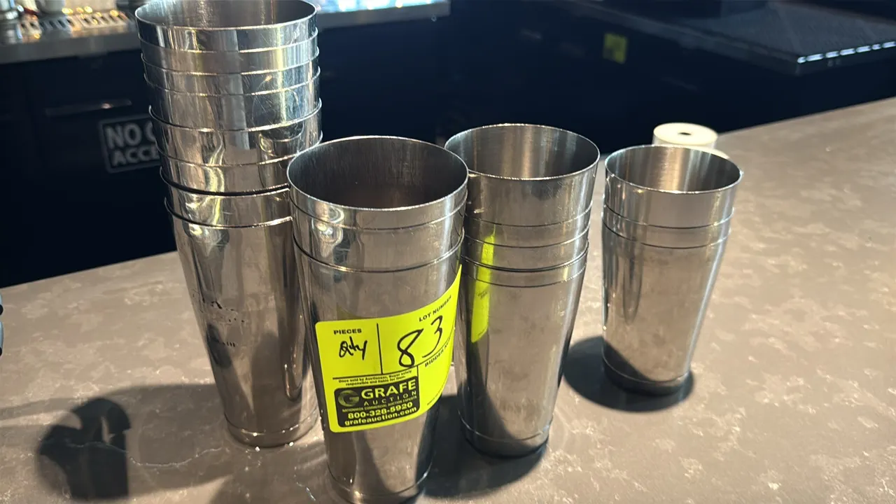Assorted stainless steel barware. Includes cocktail shaker mixing tins and assorted double-sided jiggers. Features stainless steel construction.