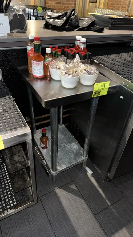 Stainless steel work table. Features a flat top and lower undershelf. 18" x 24". Mounted on tubular legs with adjustable bullet feet. Contents not inc