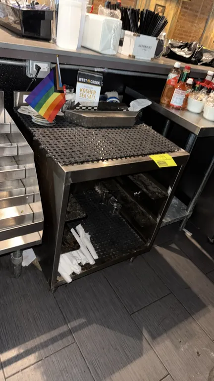 Stainless steel bar drain table cabinet. Features open-front storage base with interior rack rails and drainboard top with mesh matting. 2'W. Contents