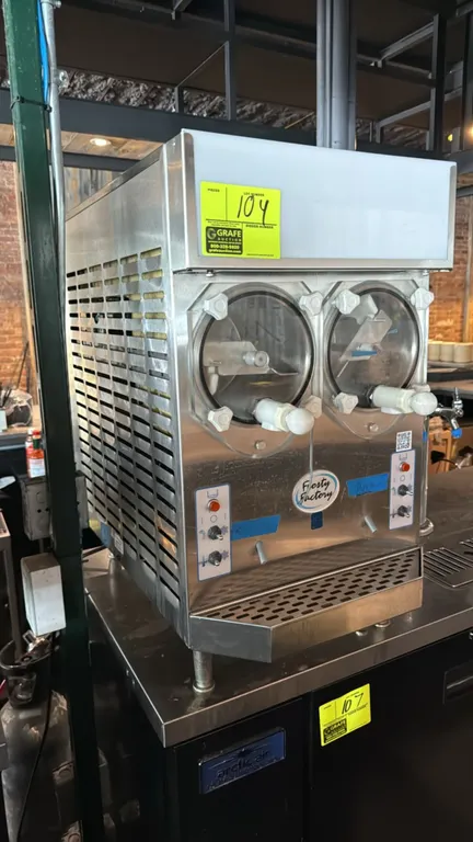 Frosty Factory 217A 2-flavor frozen drink machine. Features dual dispensing cylinders with clear faceplates, top illuminated display sign, and stainle