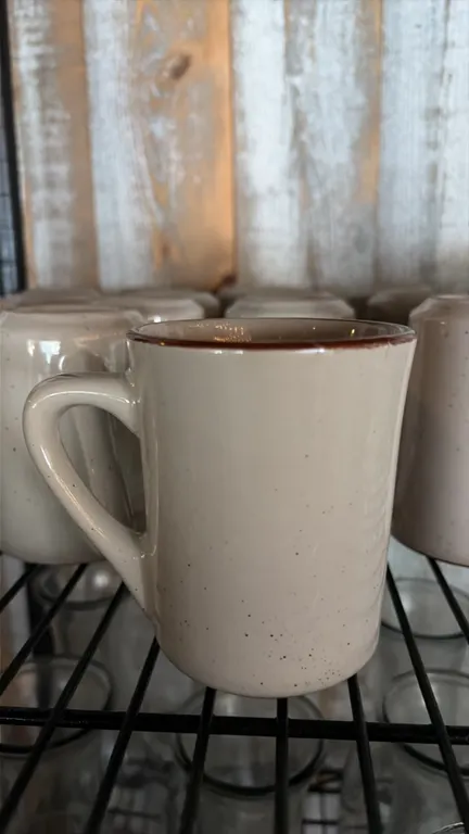 Acopa ceramic coffee cups. Includes (19) cups. Features a speckled beige finish with brown rim accent and integrated handle.