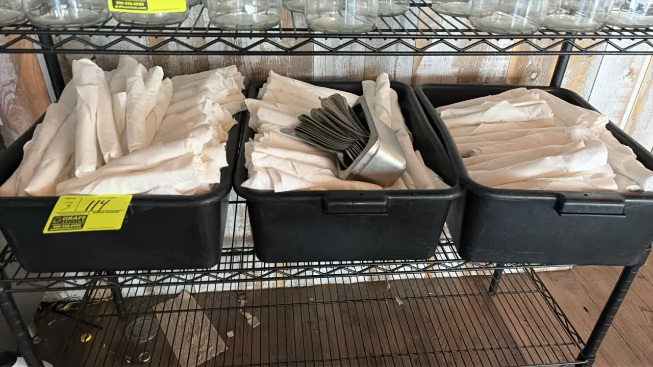 Plastic bus tubs with rolled silverware. Includes assorted flatware rolled in cloth napkins and a stainless steel insert pan containing utensils. Blac