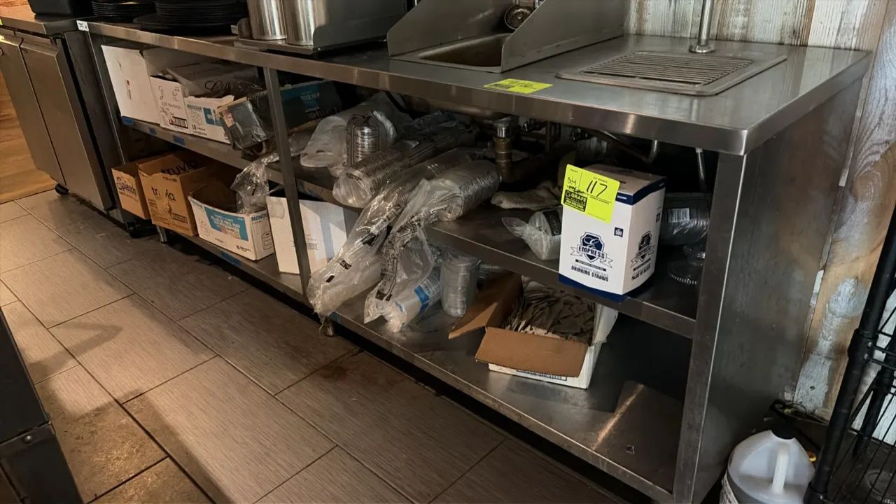 Stainless steel work table with sink and water station. Features an undershelf, integrated stainless steel sink with faucet and side splash guards, an