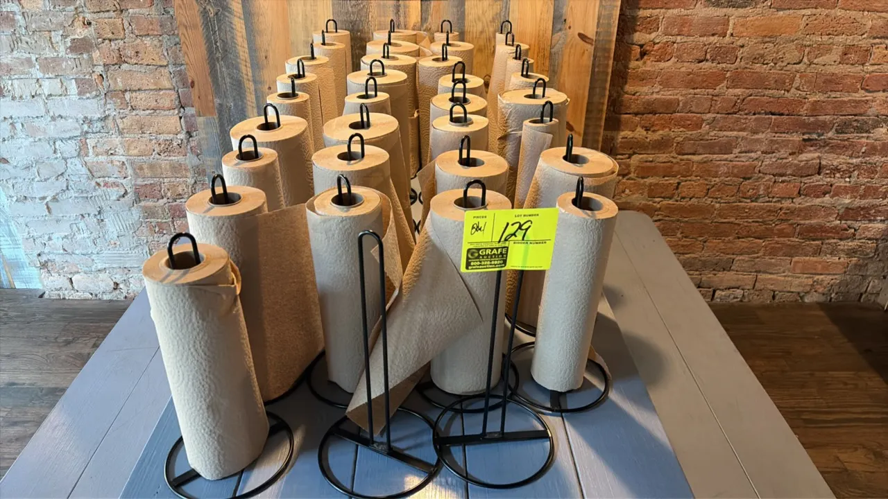 Black metal paper towel roll holders. Features wire metal construction with circular bases and top loop handles. Designed for tabletop or countertop u