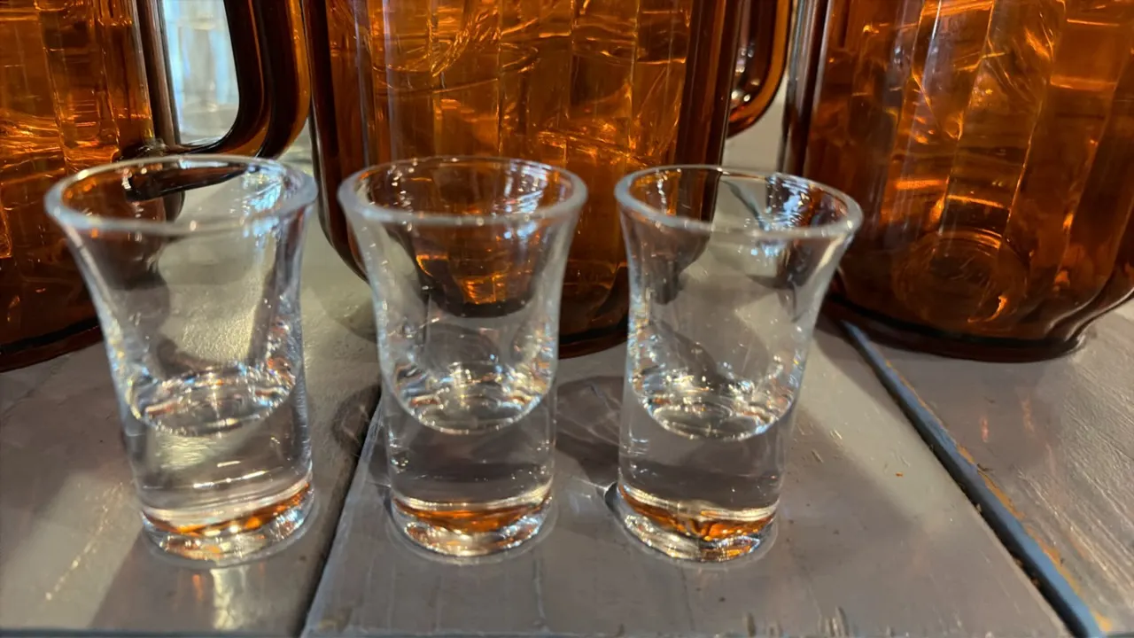 Amber plastic beverage pitchers with 1 oz shot glasses. Features fluted plastic pitcher construction with integrated side handles and pour spouts, fil