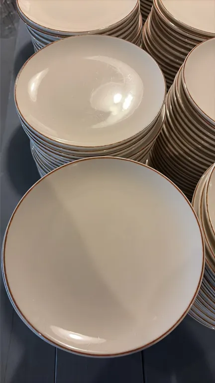 Bonna 8" porcelain plates. Includes (244) total plates. Features off-white glaze with brown rim accent. Diameter: 8". Background glassware not include