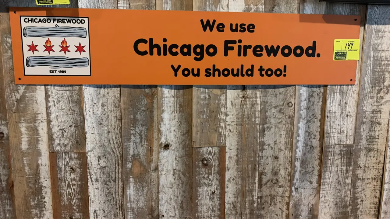 Chicago Firewood advertising sign. Features orange background with logo graphic and 'We use Chicago Firewood. You should too!' slogan. Pre-drilled cor