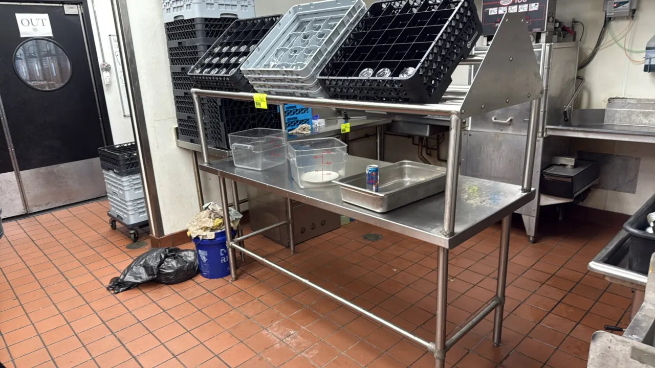 Stainless steel work table. Features a slanted dish rack overshelf and tubular overhead rack shelf. 72" x 30". Mounted on stainless steel legs with cr