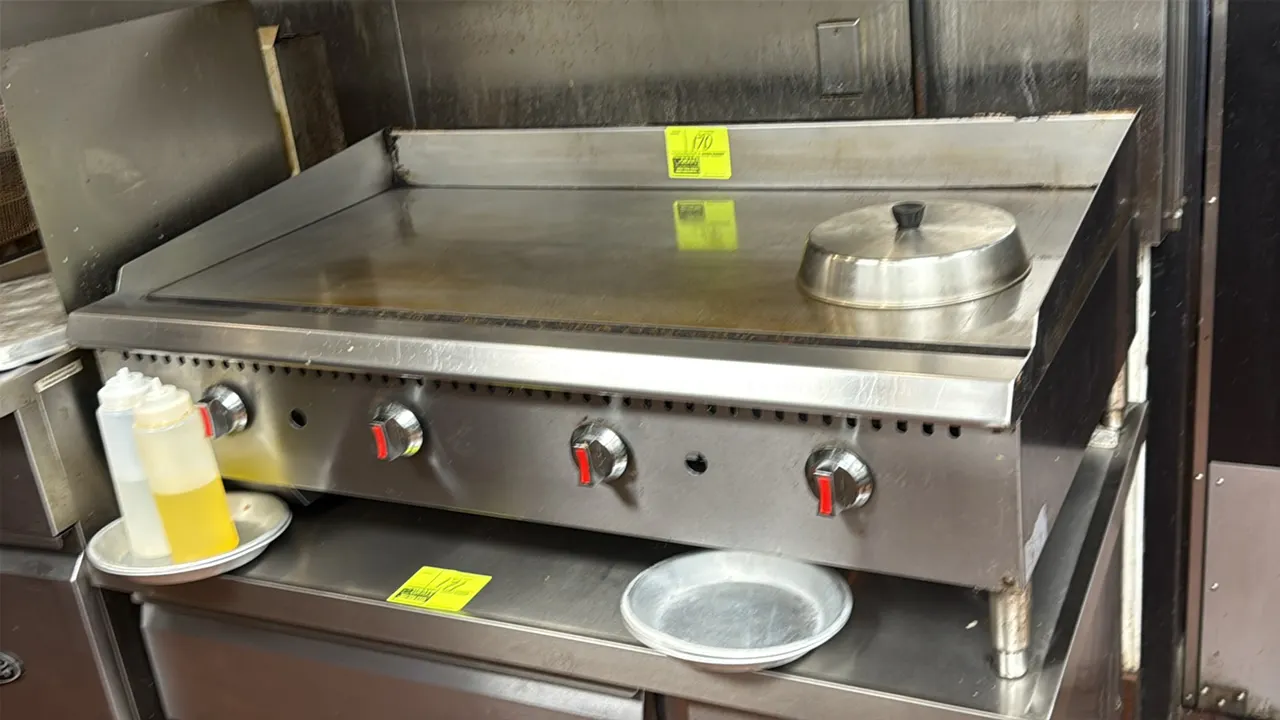 Serv-Ware gas flat griddle. Features stainless steel construction, 4 burner controls, side and rear splash guards, and front grease trough. 48"W. Gas