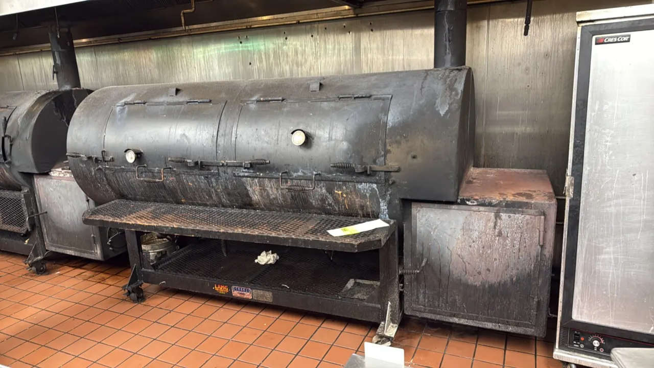 Lang portable wood smoker. Features 2-door cook chamber, right-side firebox, dual temperature gauges, multi-tier expanded metal cooking grates, front