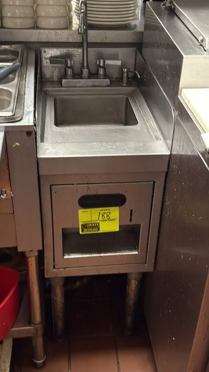 12" stainless steel hand sink. Features a splash-mounted gooseneck faucet with dual lever handles, integrated soap dispenser, built-in paper towel dis