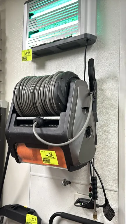 Wall-mounted electric pressure washer. Features integrated hose reel with high-pressure hose, spray gun and wand assembly, and quick-connect nozzle ti