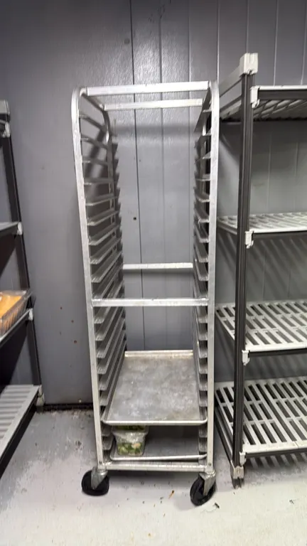 Aluminum front load channel sheet pan rack. Features 20-tier slide runners for full-size sheet pans. Mounted on swivel casters. Contents not included.