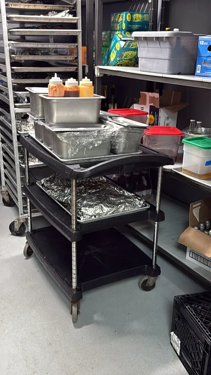 Polymer 3-tier utility cart. Features three black shelves, integrated handle, and chrome upright posts. Mounted on swivel casters. Contents not includ