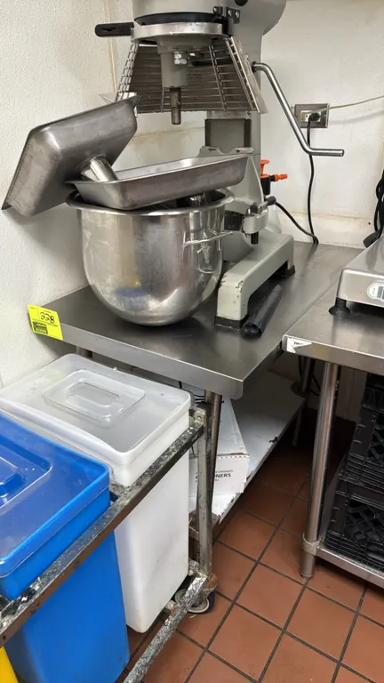 Stainless steel work table. Features an undershelf. 24" x 36". Mounted on tubular metal legs. Mixer, pans, ingredient bins, and surrounding equipment