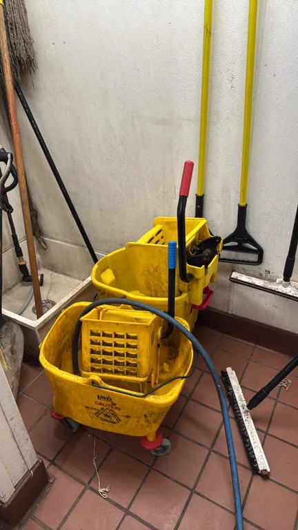 Maintenance cleaning tools and mop buckets. Includes (2) yellow plastic mop buckets with wringers on casters (one labeled Lavex), assorted mop handles