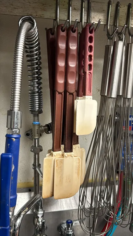 Assorted poly bowl scrapers. Features flexible scraper blades and molded composite handles with hanging holes. Whisks, pre-rinse spray assembly, and r