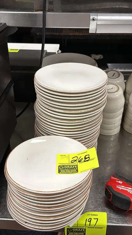 Acopa ceramic dinnerware assortment. Includes 8" plates, dinner plates, and soup bowls. Features white plates with brown rims, blue swirl shallow bowl