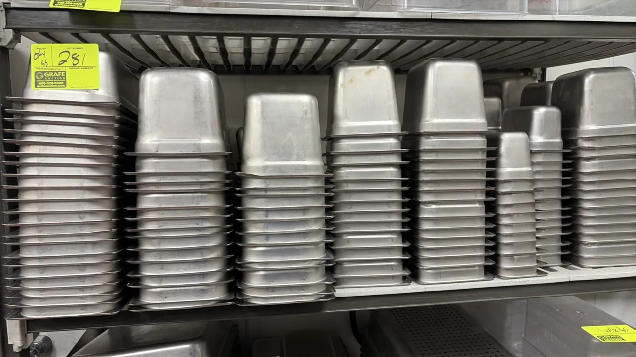 Assorted stainless steel food and steam table pans. Includes full-size hotel pans, perforated full-size pans, and various fractional-size insert pans