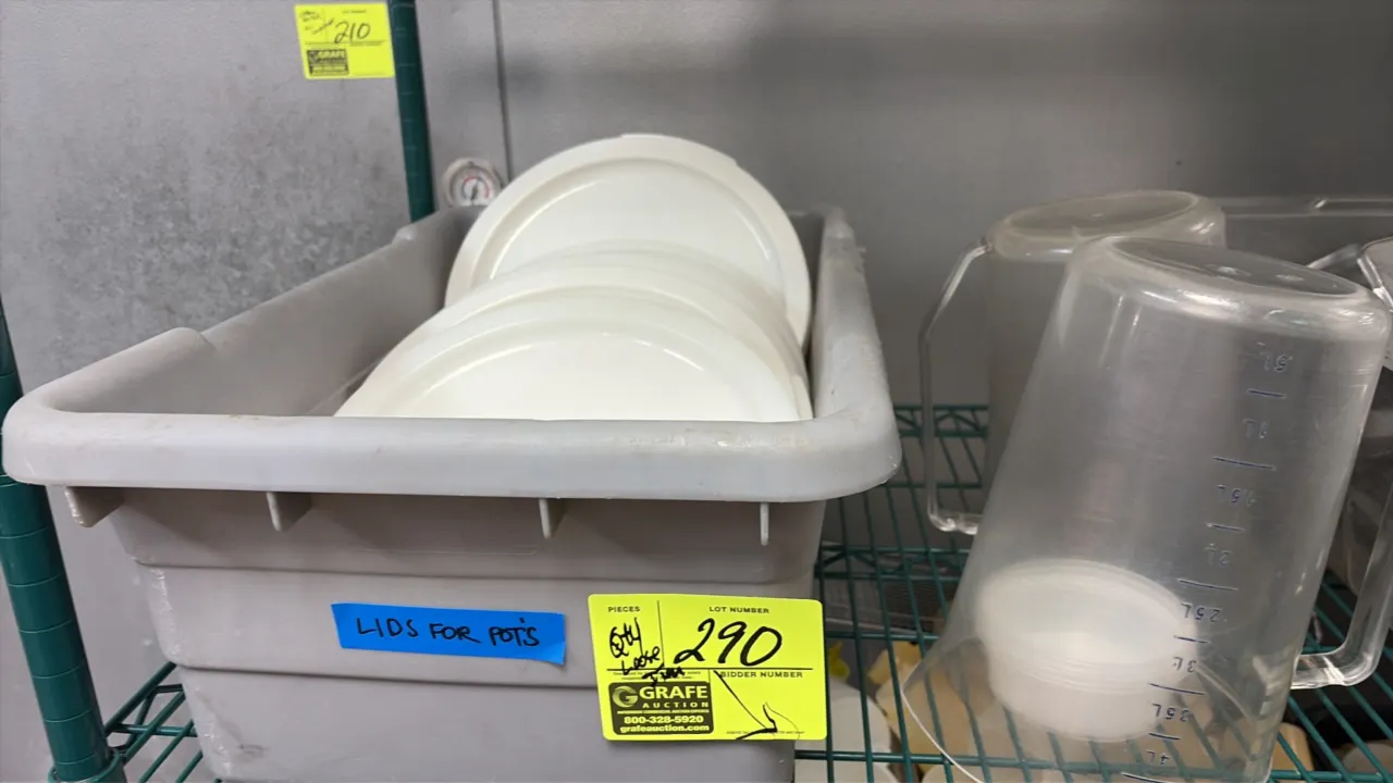 Assorted kitchen smallwares and storage containers lot. Includes plastic bus tub with round lids, measuring pitchers, plastic squeeze bottles, bar con