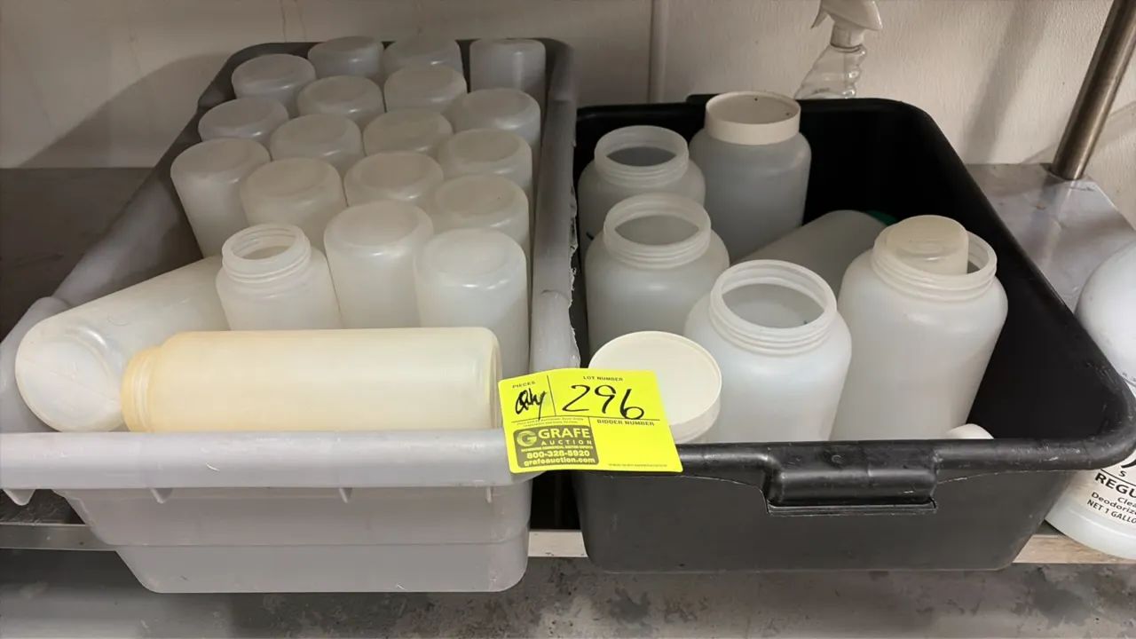 Plastic bus tubs with assorted plastic containers. Includes (1) gray and (1) black plastic bus tub filled with an assortment of translucent plastic bo