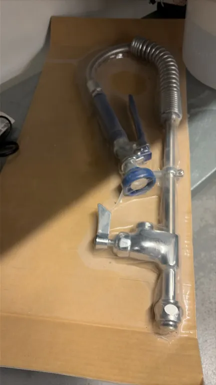 Commercial sink pre-rinse spray unit assembly. Features flexible stainless steel hose with overhead spring, spray valve with blue grip and squeeze lev