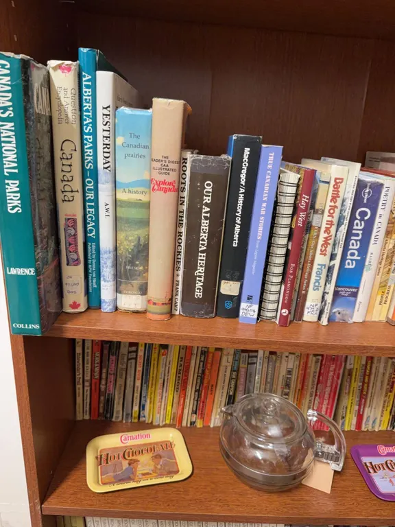 Bookshelf Lot: Canadian History Books, Western Paperbacks, Glass Teapot, Carnation Trays