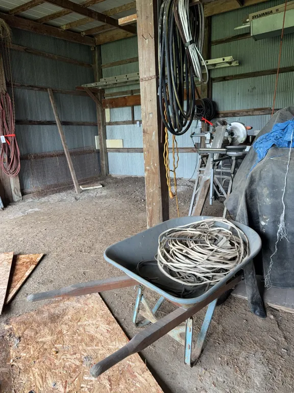 Single Wheel Wheelbarrow With Assorted Coiled Electrical Wire And Hoses