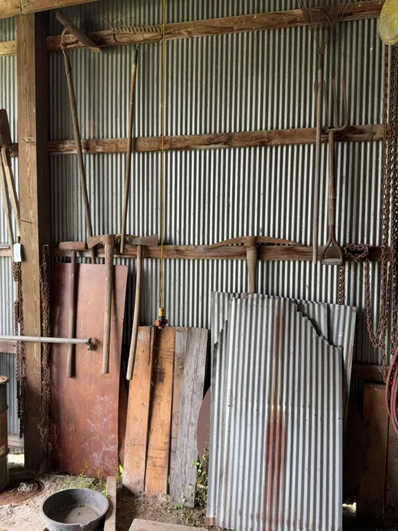 Assorted Farm Tools Sledgehammer Pickaxe Rakes and Corrugated Tin Panels