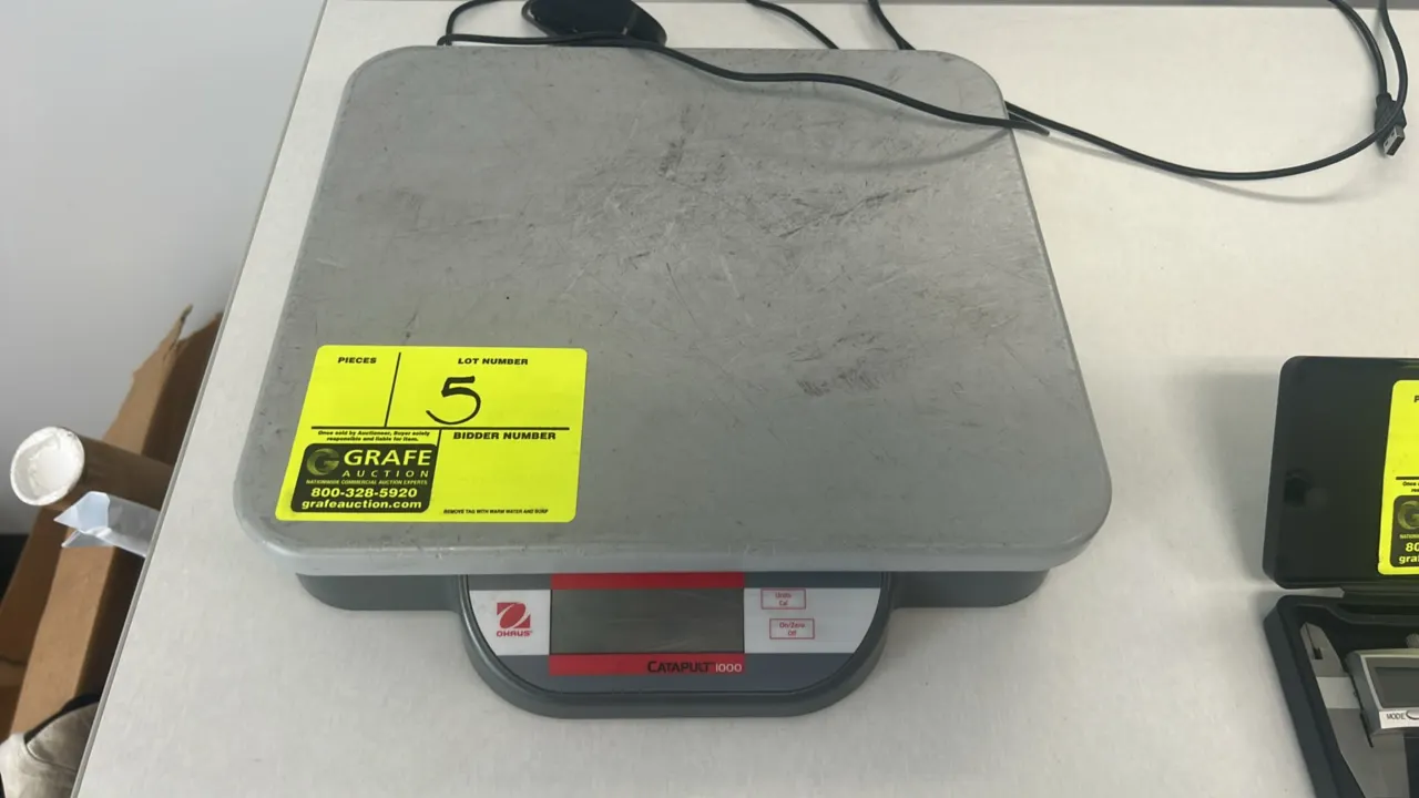 OHAUS Catapult 1000 compact bench scale. Features digital LCD display, two-button operation (Units/Cal and On/Zero/Off), and durable composite platfor