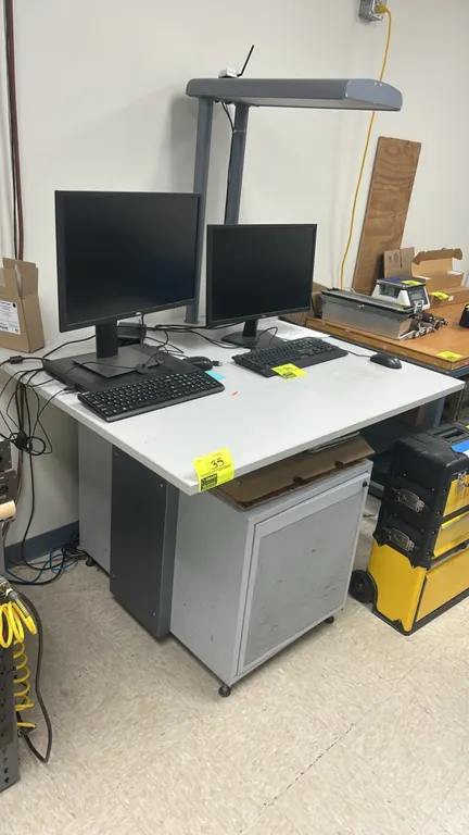 Metal workstation cabinet with laminate top. Features an attached overhead task light, ventilated enclosure cabinet with perforated door, and adjustab