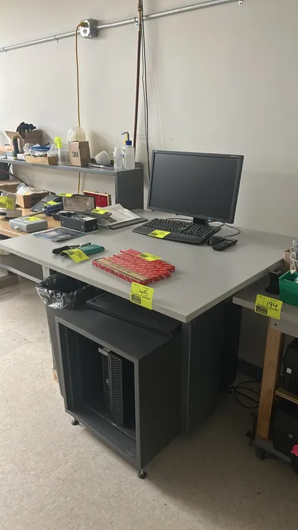 Metal workstation cabinet with laminate top. Features a gray laminate work surface, painted steel frame construction, and lower equipment enclosure wi