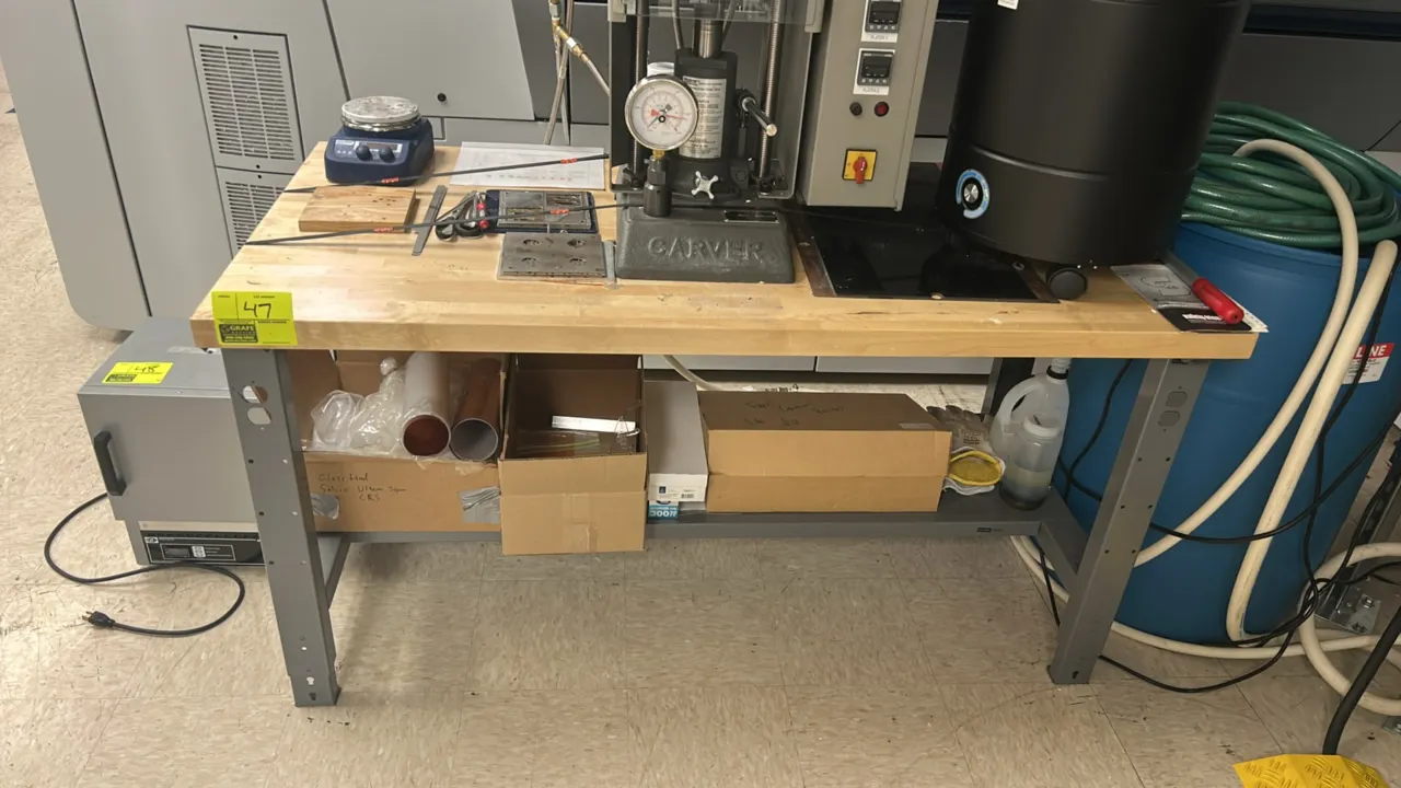 Industrial workbench. Features a solid wood butcher block top, lower metal storage shelf, and gray painted steel frame with adjustable-height legs. 60