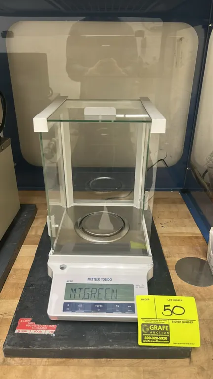 Mettler Toledo ME54E analytical balance. Features glass draft shield with three sliding doors, stainless steel weighing pan, front leveling bubble, ba