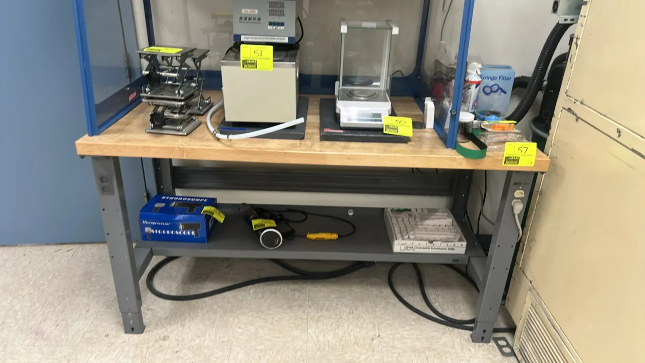 Industrial workbench. Features a butcher block wood top, painted steel frame, lower undershelf, and integrated electrical duplex outlets on legs. 60"