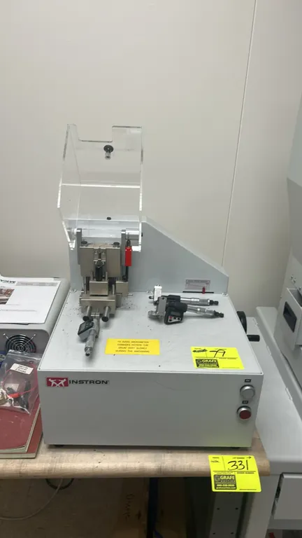 Instron CEAST specimen notching machine. Features a protective clear safety shield, notch speed variator control, push-button operation, and digital m
