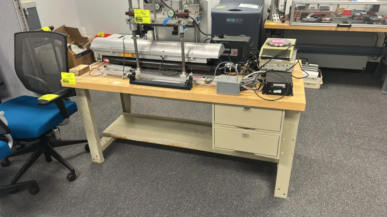 Wooden workbench with metal base. Features a butcher block style wood top, painted metal frame, lower utility shelf, and 2-drawer side storage unit. 6