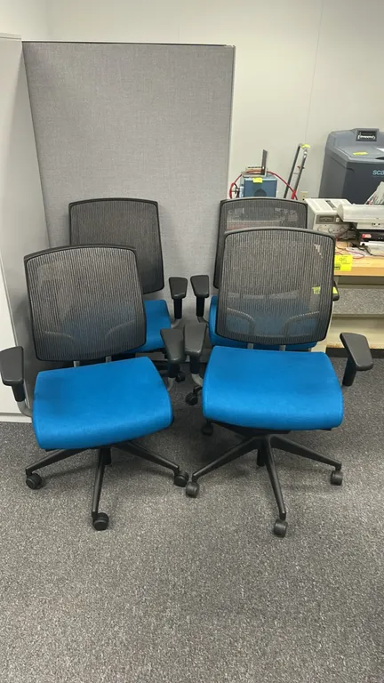 Mesh-back office chairs. Features a black mesh back, blue fabric upholstered seat, and adjustable armrests. Mounted on a 5-star base with rolling cast