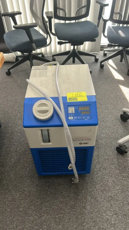 2021 SMC HRS012-AN-10 compact thermo-chiller. Features digital control display, front fluid level sight gauge, top fill port, and attached transfer ho