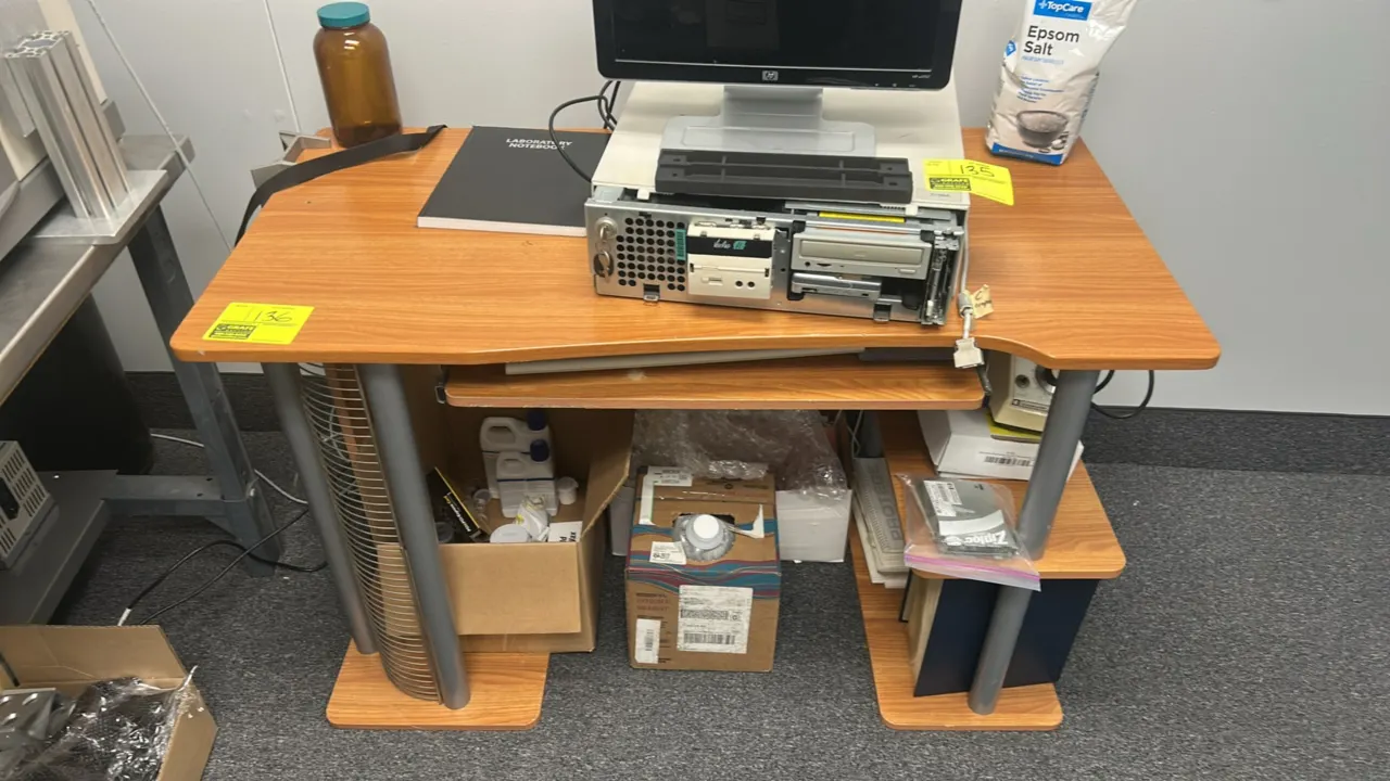 Computer desk. Features woodgrain laminate surfaces, pull-out keyboard tray, integrated wire media storage rack, and two tiered side shelves. 4'L x 2'
