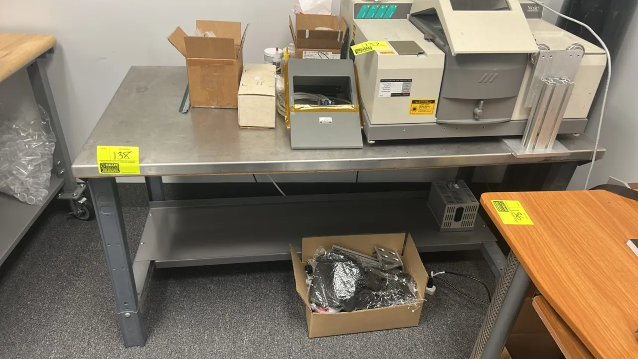 Metal workbench. Features a stainless steel work surface, painted steel frame, and lower shelf. 60" x 30". Contents not included.