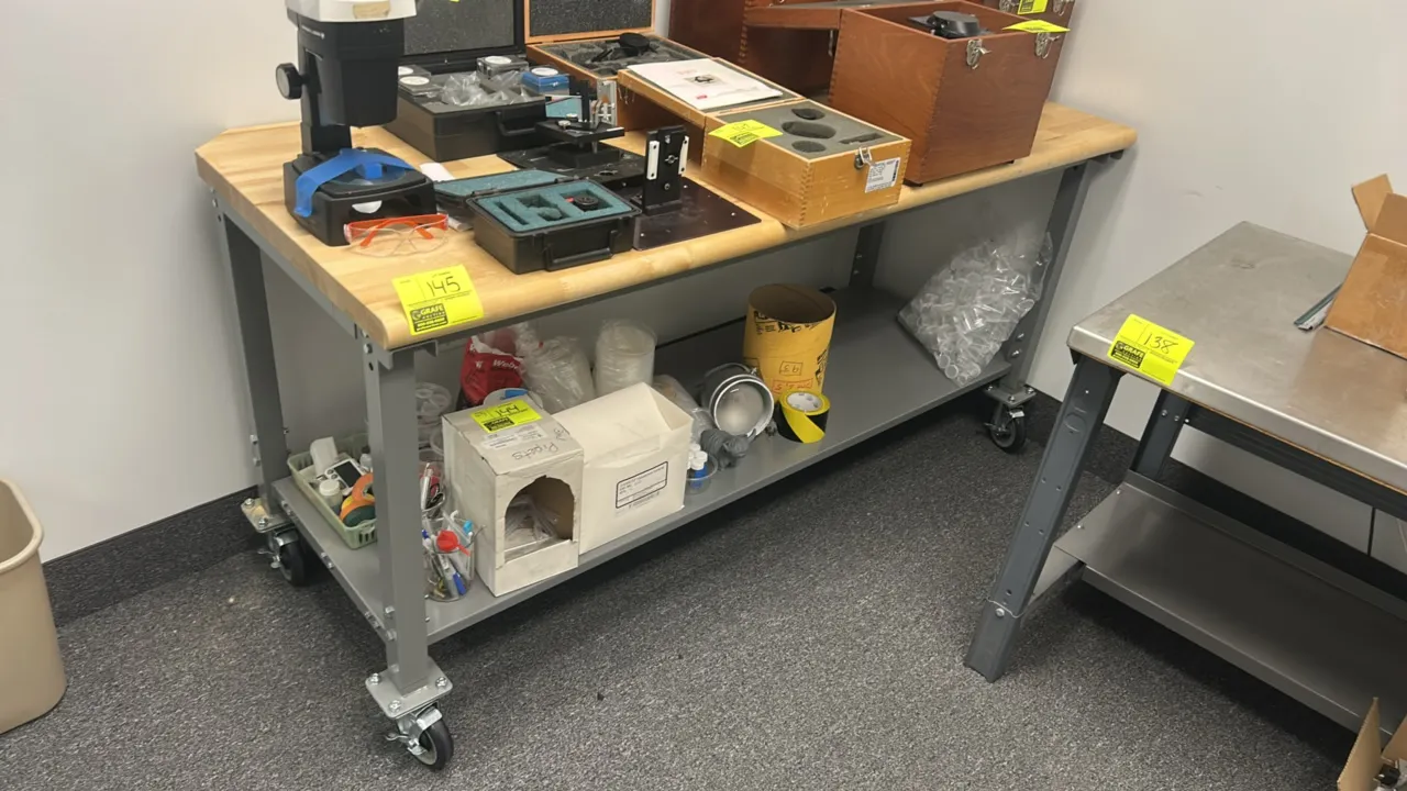 Mobile 2-tier work table. Features a butcher block wood top and metal frame with lower shelf. 72" x 30". Mounted on swivel casters. Contents not inclu