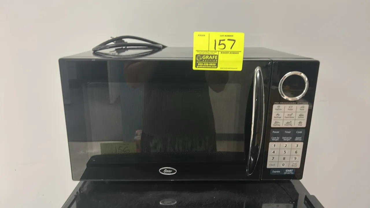 Oster countertop microwave oven. Features digital touchpad controls with pre-programmed settings, glass turntable, and black finish with chrome pull h