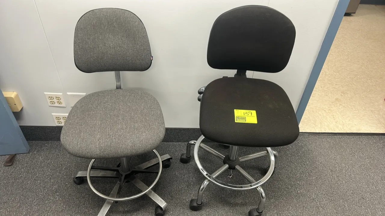 Rolling drafting office chairs. Includes (1) gray fabric and (1) black fabric chair. Features cushioned seats and backrests, adjustable height, armles